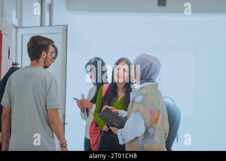 Dans le couloir d'une école, un groupe diversifié d'étudiants prend une pause de leurs classes, s'engageant dans des conversations animées qui reflètent la riche tapisserie de Banque D'Images