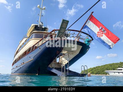 Passagers nageant à la marina arrière intégrée du yacht de luxe MON Casablanca en Croatie, beau petit bateau de croisière classique, drapeau national croate Banque D'Images