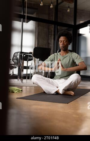 Heureux homme afro-américain détendu pratiquant le yoga respiration profonde assis à la maison, espace de copie Banque D'Images