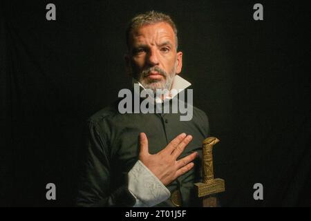 Homme vêtu d'un col noir et blanc avec un geste sérieux qui ressemble à l'homme du Chevalier de la main sur la poitrine d'El Greco sur un backgrou noir Banque D'Images