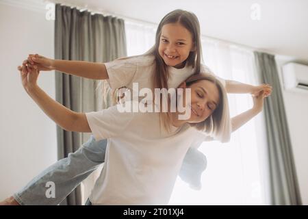 Une belle petite fille et sa mère aiment le soleil matin. Bon séjour à la maison. Banque D'Images