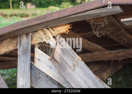 Les restes d'un vieux toit détruit reposent sur le sol après la démolition de la grange. Jour. Banque D'Images