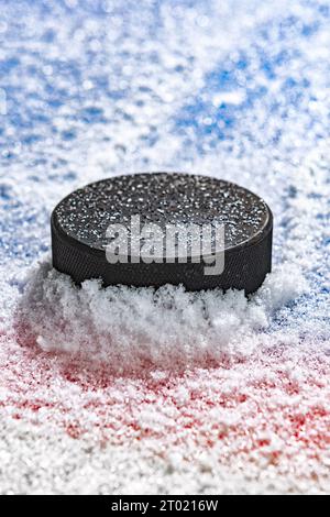Palet de hockey sur glace noir déblayant la neige et s'arrêtant sur le bord de la ligne de but du pli de but. Banque D'Images
