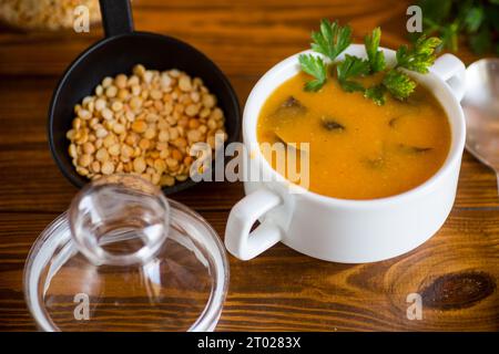 Soupe de purée de pois séchés cuite avec des champignons dans un bol sur une table en bois sombre. Banque D'Images