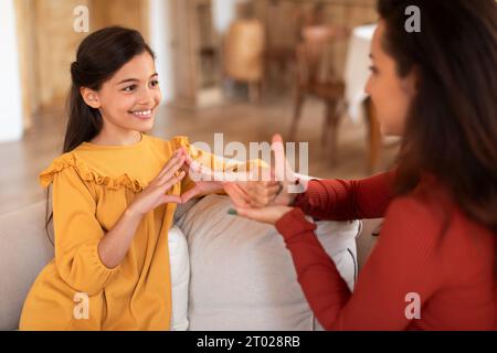 Fille faisant le geste de la main en utilisant la langue des signes avec Tutor Indoor Banque D'Images