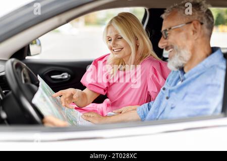 Heureux amis retraités voyageant ensemble en voiture, vérifier la carte Banque D'Images