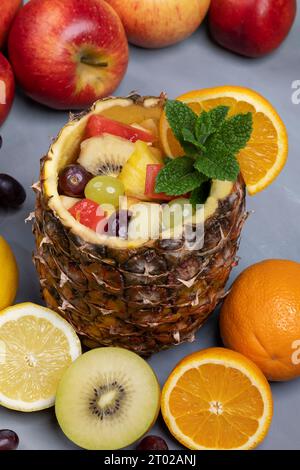 salade de fruits frais servie dans un ananas creux, décoré de fruits et de menthe Banque D'Images