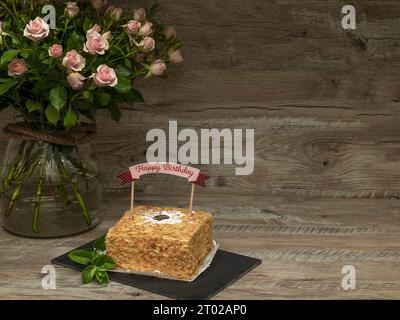 Gâteau d'anniversaire avec écriture Joyeux anniversaire. Décoré avec un grand bouquet de roses et espace de copie Banque D'Images