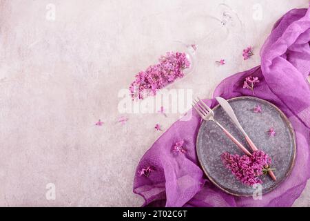 Table avec verre rempli de fleurs lilas Banque D'Images