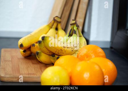 bananes sur une planche de bois dans une cuisine avec des oranges et du citron Banque D'Images