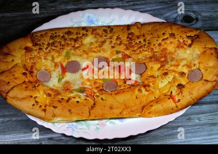 Fromage Fougasse recouvert de tranches de poivrons verts, de fromage et de saucisses coupées cuites au four, le pain de fougasse est un type de pain typiquement associé Banque D'Images