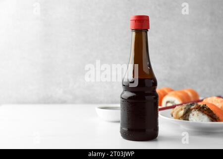 Sauce soja savoureuse et différents types de sushi sur table blanche. Espace pour le texte Banque D'Images