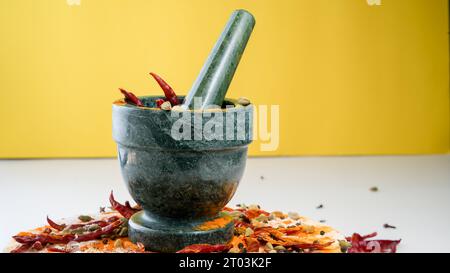 Mortier de granit et pilon avec des épices colorées avec fond jaune Banque D'Images