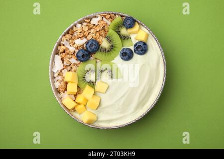 Savoureux bol de smoothie matcha servi avec des fruits frais et des flocons d'avoine sur fond vert, vue de dessus. Petit déjeuner sain Banque D'Images