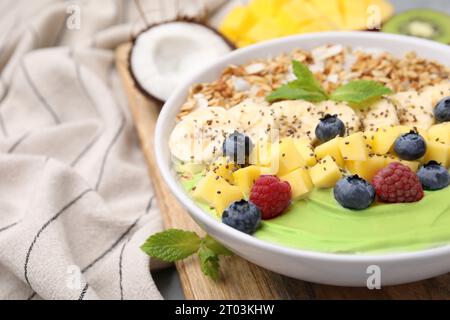 Savoureux bol de smoothie matcha servi avec des fruits frais et des flocons d'avoine sur la table, gros plan avec espace pour le texte. Petit déjeuner sain Banque D'Images