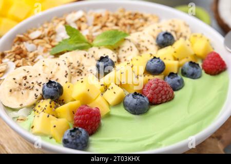 Savoureux bol de smoothie matcha servi avec des fruits frais et des flocons d'avoine sur la table, gros plan. Petit déjeuner sain Banque D'Images