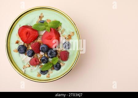 Savoureux bol de smoothie matcha servi avec des baies et des flocons d'avoine sur fond beige, vue de dessus avec espace pour le texte. Petit déjeuner sain Banque D'Images