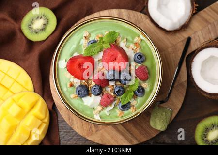 Savoureux bol de smoothie matcha servi avec des fruits frais et des flocons d'avoine sur une table en bois, plat. Petit déjeuner sain Banque D'Images