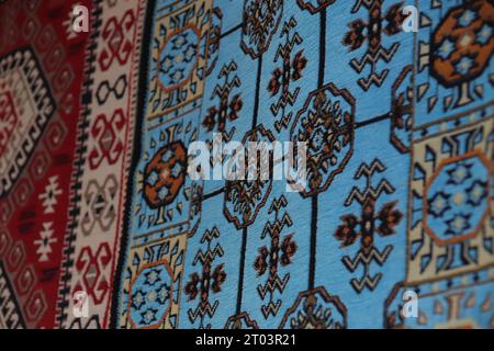 Deux beaux tapis tissés à motifs ethniques, un bleu et un rouge, accrochés à un mur exposé dans les rues de Gjirokaster Baazar en Albanie. Banque D'Images