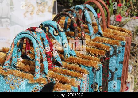 Une rangée de fourre-tout ou sacs à main excentriques, uniques, brodés soyeux, multicolores, avec poignées rigides arquées, Golden Tufts et divers motifs de conception. Banque D'Images