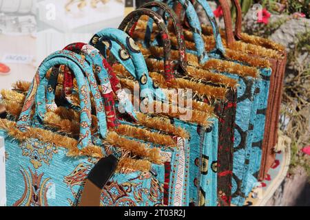 Une rangée de fourre-tout ou sacs à main excentriques, uniques, brodés soyeux, multicolores, avec poignées rigides arquées, Golden Tufts et divers motifs de conception. Banque D'Images