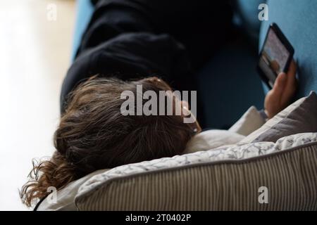 Berlin, Allemagne. 28 septembre 2023. Une femme est allongée sur un canapé regardant une vidéo sur la plateforme de médias sociaux Instagram sur son téléphone. Crédit : Weronika Peneshko/dpa/Alamy Live News Banque D'Images