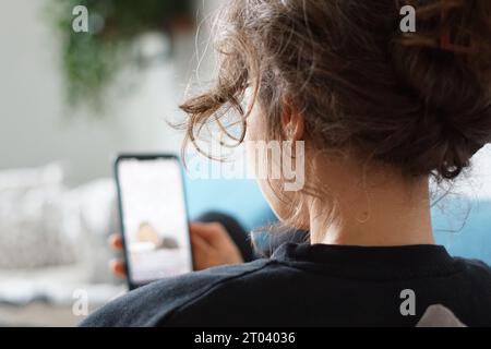 Berlin, Allemagne. 28 septembre 2023. Une femme s’allonge sur un canapé et regarde une vidéo sur la plateforme de médias sociaux Instagram sur son téléphone portable. (À dpa '#thérapie : Pseudopsychologie dans les médias sociaux et ses conséquencess') crédit : Weronika Peneshko/dpa/Alamy Live News Banque D'Images