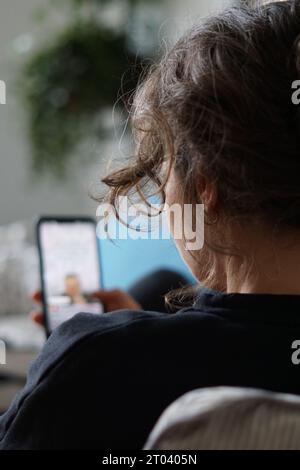 Berlin, Allemagne. 28 septembre 2023. Une femme est allongée sur un canapé regardant une vidéo sur la plateforme de médias sociaux Instagram sur son téléphone. Crédit : Weronika Peneshko/dpa/Alamy Live News Banque D'Images