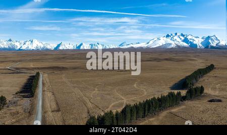 Longue route de gravier sinueuse et étroite à travers la campagne agricole rurale vers la chaîne de montagnes enneigée des alpes du Sud Banque D'Images