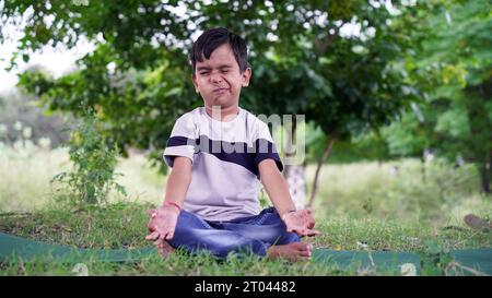 Portrait de magnifique enfant pratiquant le yoga en plein air. Bel enfant pratique le yoga asana ou fait des exercices de gymnastique. Petits enfants méditant dans lotus po Banque D'Images