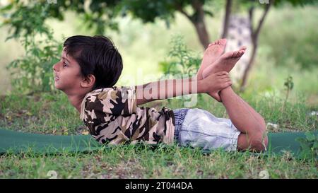 Portrait de magnifique enfant pratiquant le yoga en plein air. Bel enfant pratique le yoga asana ou fait des exercices de gymnastique. Petits enfants méditant dans lotus po Banque D'Images