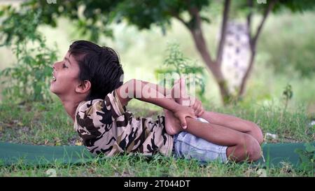 Portrait de magnifique enfant pratiquant le yoga en plein air. Bel enfant pratique le yoga asana ou fait des exercices de gymnastique. Petits enfants méditant dans lotus po Banque D'Images