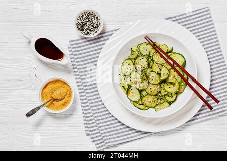 Sunomono, salade japonaise de concombres, tranches de concombres avec sauce asiatique de soja, vinaigre de riz, huile de sésame et sucre dans un bol blanc avec baguettes Banque D'Images