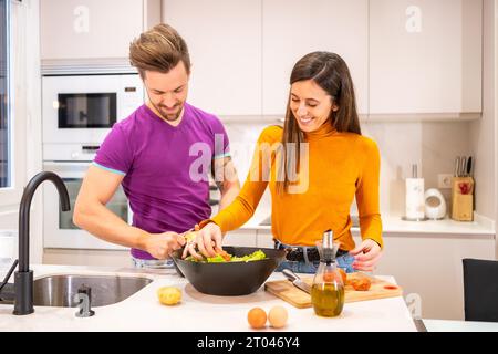 Couple préparant des aliments sains dans une cuisine domestique à la maison Banque D'Images