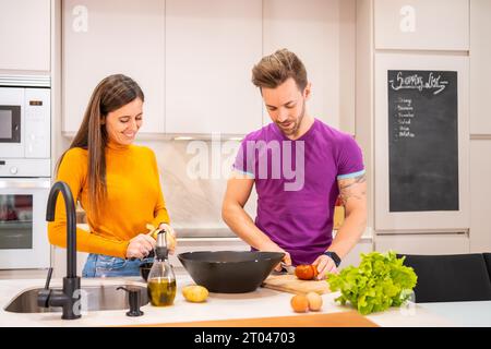 Vue frontale d'un couple préparant une salade saine à la maison Banque D'Images