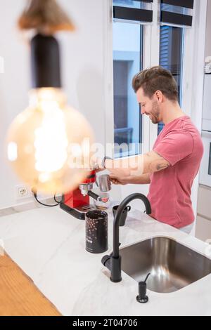 Photo verticale d'un homme préparant un café à la maison avec une machine à café électrique Banque D'Images