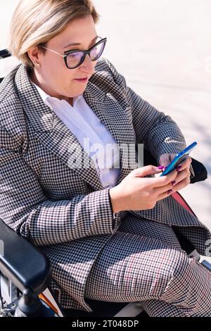femme d'affaires utilisant un fauteuil roulant utilisant un mobile Banque D'Images
