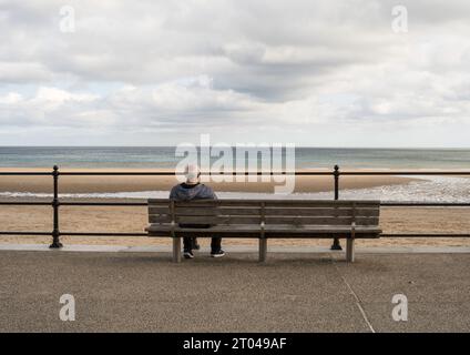 Un homme âgé assis seul regardant la mer à Roker, Sunderland, Angleterre, Royaume-Uni Banque D'Images