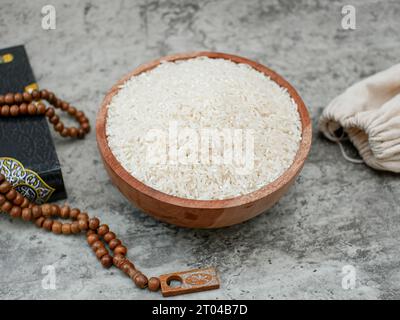 saint Coran et un grain de riz dans un bol en bois. Concept de zakat islamique Banque D'Images