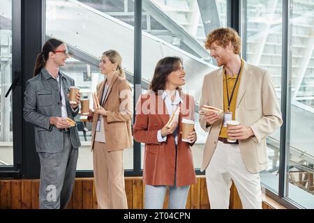 quatre collègues créatifs ayant une pause déjeuner dégustation de sandwichs et de café, concept de coworking Banque D'Images