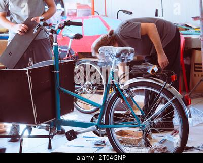 au magasin de vélo et de réparation, vieux mécanicien caucasien réparations expert assemblant vélo de cargaison Banque D'Images