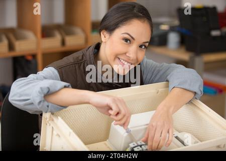 heureuse femme technicien câblant les câbles dans la boîte Banque D'Images