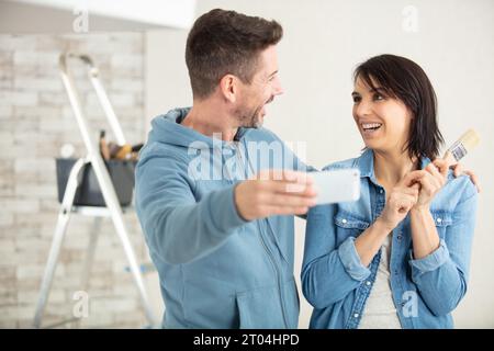 couple à la maison peinture murs prenant selfie avec smartphone Banque D'Images