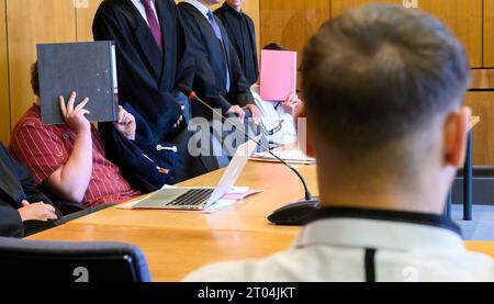 Hildesheim, Allemagne. 04 octobre 2023. Les trois accusés siègent au tribunal régional de Hildesheim et couvrent leur visage. Plus d'un an après que deux couvercles de trou d'homme ont été jetés d'un pont sur l'autoroute A7, trois hommes doivent être jugés devant le tribunal régional. Les trois accusés sont accusés de tentative de meurtre combinée à des blessures corporelles dangereuses et à des perturbations dangereuses dans la circulation. Crédit : Julian Stratenschulte/dpa/Alamy Live News Banque D'Images