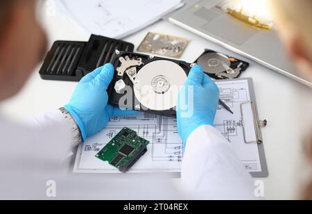 Le technicien répare le disque dur de l'ordinateur à partir de la carte mère Banque D'Images