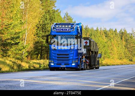 Le camion bleu Scania S500 Hosike transporte un véhicule de sauvetage militaire de la Croix-Rouge sur une remorque de chargement basse le jour de l'automne. Raasepori, Finlande. 22 septembre 2023. Banque D'Images