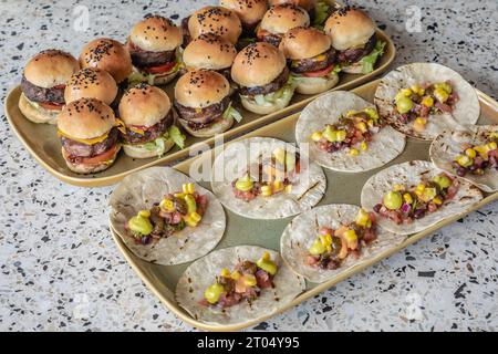 Une image en gros plan présente une gamme de délicieux mini burgers et rotis, astucieusement disposés sur des plateaux, promettant un voyage culinaire sous forme mini Banque D'Images