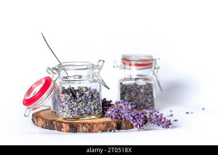 Fleurs de lavande parfumées dans de petits bocaux en verre sur fond blanc. Ils peuvent être utilisés en aromathérapie, en cosmétique, en médecine alternative et en nutrition Banque D'Images