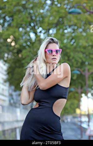 Portrait d'une femme blonde aux cheveux longs en robe noire fendue, Banque D'Images