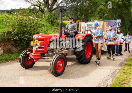 Les villageois vêtus de costumes traditionnels participent fièrement à la parade annuelle des vaches alpines dans le village de Lignières, dans les montagnes du Jura, en Suisse. Banque D'Images